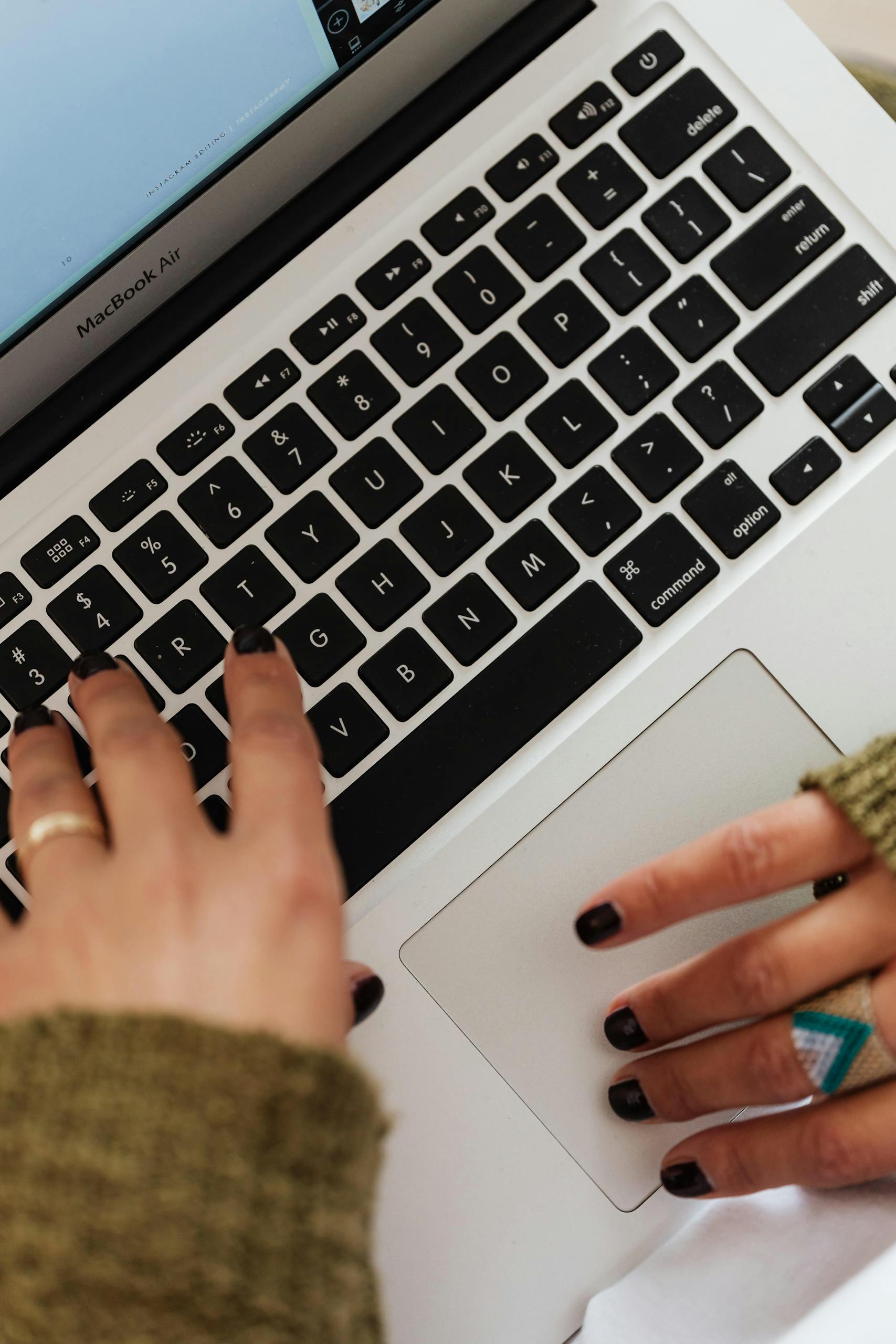 Close-up of hands typing on a MacBook Air keyboard, creating a focused work environment.