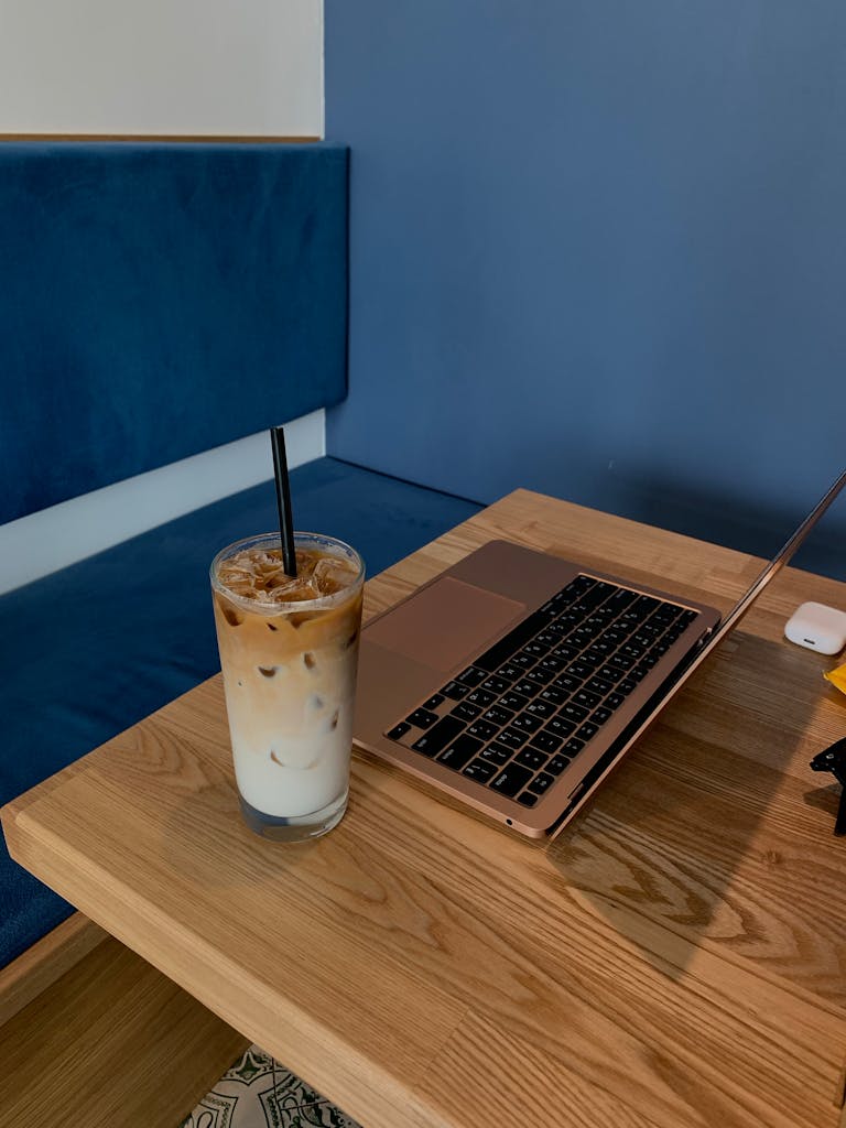 Serene workspace setting with an iced coffee and open laptop on a wooden table.