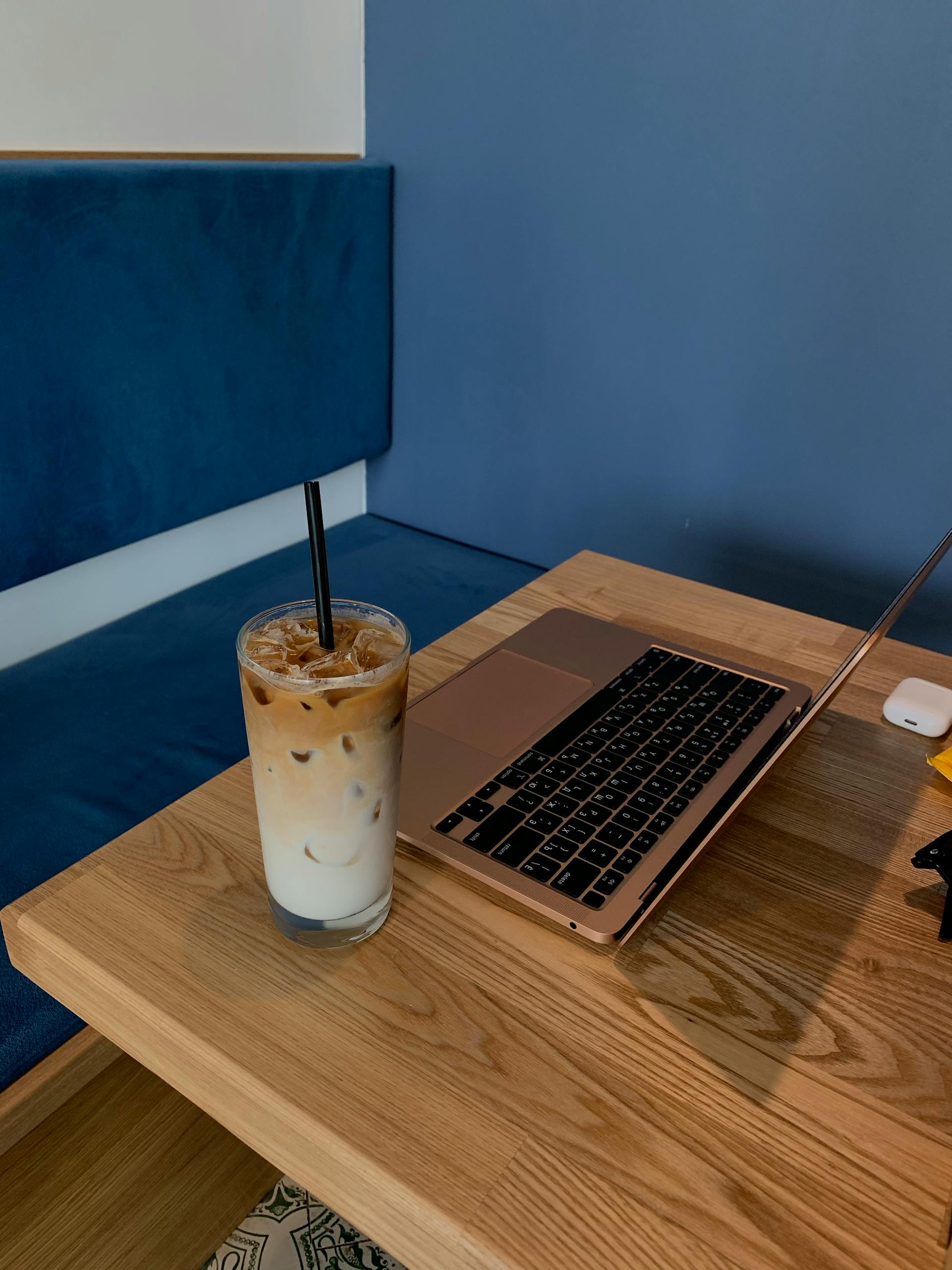 Serene workspace setting with an iced coffee and open laptop on a wooden table.