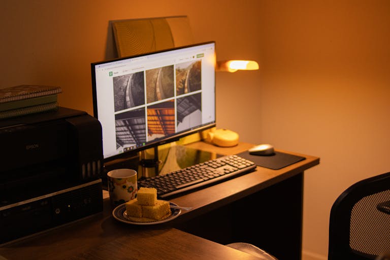 Warm-toned home office with computer setup, snacks, and ambient lighting.